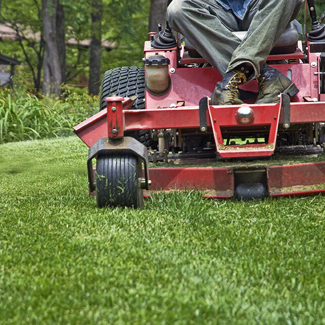 Closeup of a riding mower cutting the grass.